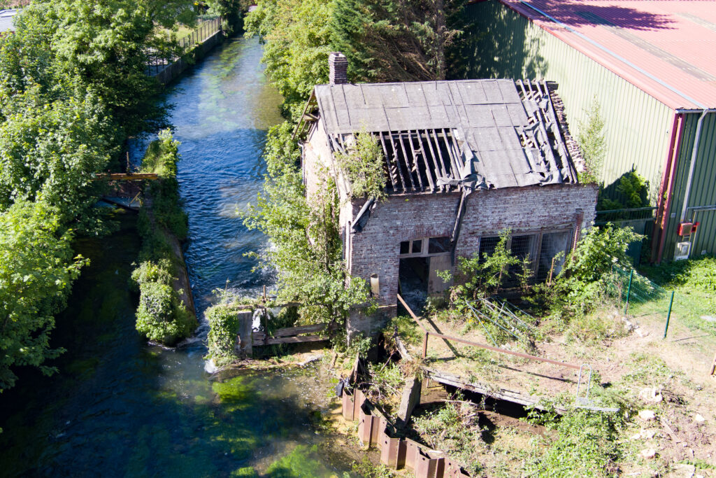 Vue du bâtiment d'un ancien moulin en état de délabrement et de la rivière située à proximité